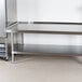 An Advance Tabco stainless steel equipment stand with an undershelf under a stainless steel work table.