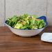 A Santa Lucia melamine bowl filled with salad on a table.