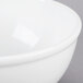 A close-up of a white Cal-Mil melamine bowl with a white rim.