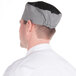 A man wearing a Chef Revival black and white checkered baker's skull cap.