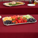 A Vollrath stainless steel serving tray of fruit and vegetables on a table.