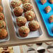 A white Cambro market tray of muffins and croissants on a bakery display counter.