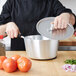 A chef uses a Vollrath Wear-Ever sauce pan to cook tomatoes.