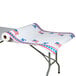 A roll of 40" x 300' patriotic paper table cover with red and blue designs on a table.