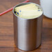 An American Metalcraft stainless steel round sugar packet holder filled with yellow papers.