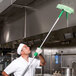 A man in a white coat and hat using a Unger microfiber sleeve on a green handle to clean a kitchen.