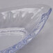 A clear glass dish with a banana split in it on a white surface.
