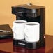 A Conair Cuisinart coffee maker with two white mugs.