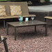 A Grosfillex Fusion Bronze aluminum cocktail table on a patio with wine glasses on it.