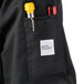 A close up of a Mercer Culinary black chef jacket pocket with a pen and a pencil in it.