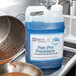 A blue container of Noble Chemical Pan Pro soap on a counter next to a pot and pan.