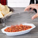 A hand holding a Fineline clear plastic container with salsa and a dome lid.