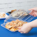 A person holding a Fineline clear plastic serving tray with food inside.
