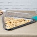 A Fineline black plastic triangular tray with cookies on a table.