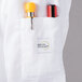 A white Mercer Culinary chef coat pocket with a pen and a bottle.