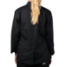 The back of a woman wearing a black Mercer Culinary long sleeve chef jacket.