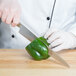 A person in white gloves using a Mercer Culinary MX3 Sujihiki Knife to cut a green bell pepper.