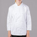 A young woman wearing a Mercer Culinary white long sleeve chef jacket.