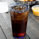 A Cambro slate blue plastic tumbler filled with ice tea on a table with a bowl of fries.