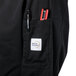 The pocket of a black Mercer Culinary Genesis long sleeve chef jacket with a pen and a marker.