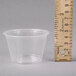 A clear plastic Dart souffle cup with a ruler next to it.
