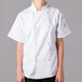 A young woman wearing a Mercer Culinary white short sleeve chef jacket.