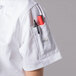 A person wearing a Mercer Culinary white chef jacket with a pen in the pocket.