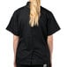 A woman wearing a Mercer Culinary black short sleeve chef jacket with cloth knot buttons.