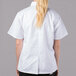 A woman wearing a white Mercer Culinary short sleeve chef jacket.