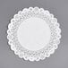 A white paper doily with a white border on a gray surface.