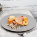 A 10 Strawberry Street matte gray stoneware plate with food and a fork on a table.
