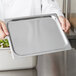 A person holding a Vollrath stainless steel rectangular tray with a salad.