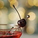A glass of cherry juice with a Regal purple maraschino cherry with a stem on top.