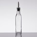 A Choice glass oil and vinegar cruet with metal pourer on a table.