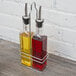 A metal stand with 12 Choice oil and vinegar cruet bottles filled with yellow liquid.