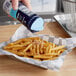 A hand pouring Morton Fine Sea Salt on french fries.