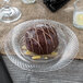 A round chocolate dessert on a Visions clear plastic plate with white stripes.