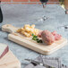 A Choice wooden serving and cutting board with food on it, including a knife slot.