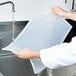 A person washing a Flexsil high-heat silicone steam table lid in a sink.