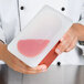 A chef using a Flexsil lid on a plastic container of pink liquid.