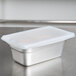 A white high-heat silicone lid on a stainless steel container.