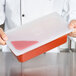 A chef using a Flexsil high-heat silicone lid on a plastic container of red liquid.
