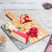 An American Metalcraft olive wood and marble serving board with cheese and fruit.