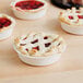 A group of small pies with lattice crusts and Lucky Leaf cherry pie filling in white bowls.