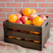 A wooden crate filled with oranges and apples on a table.
