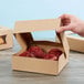 A hand opening a Kraft bakery box with a red muffin inside.