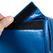 A hand holding a blue Cres Cor bun pan rack cover with a zipper.