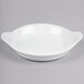 A white bowl with a handle on a gray surface.