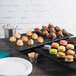 An Elite Global Solutions black slate melamine tray with desserts and cookies on a table.