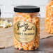 A jar of Grandma Jack's Gourmet Gold Cheddar Popcorn on a table with a label.